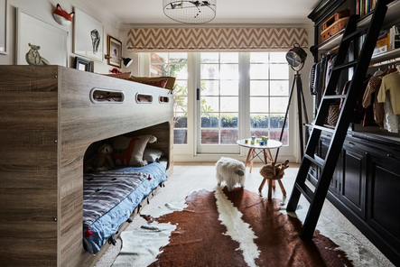 This small bedroom is jam-packed with architectural detailing and kid-friendly knick-knacks. Fun prints like the window treatment and quilts bring life to this space, and floor-length windows flood in so much natural light!